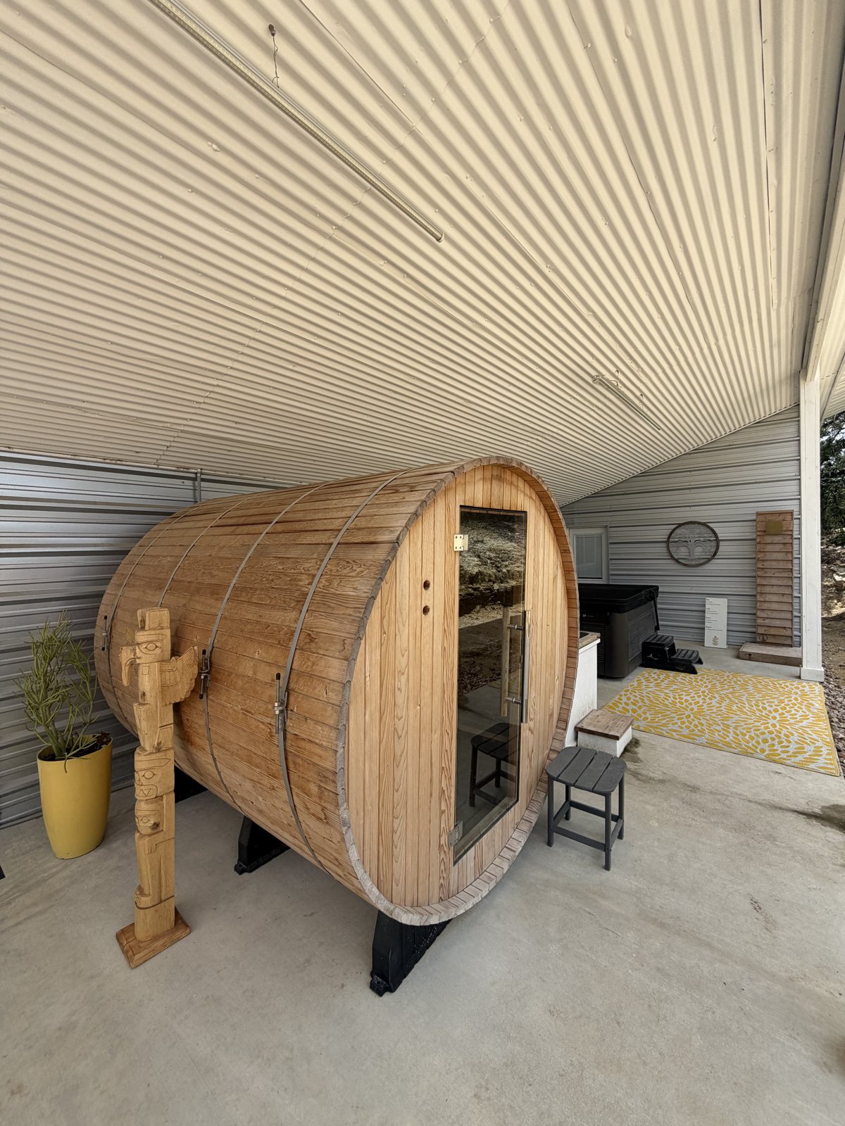 Cedar barrel sauna with hand-carved totem at AWKN Wellness Center