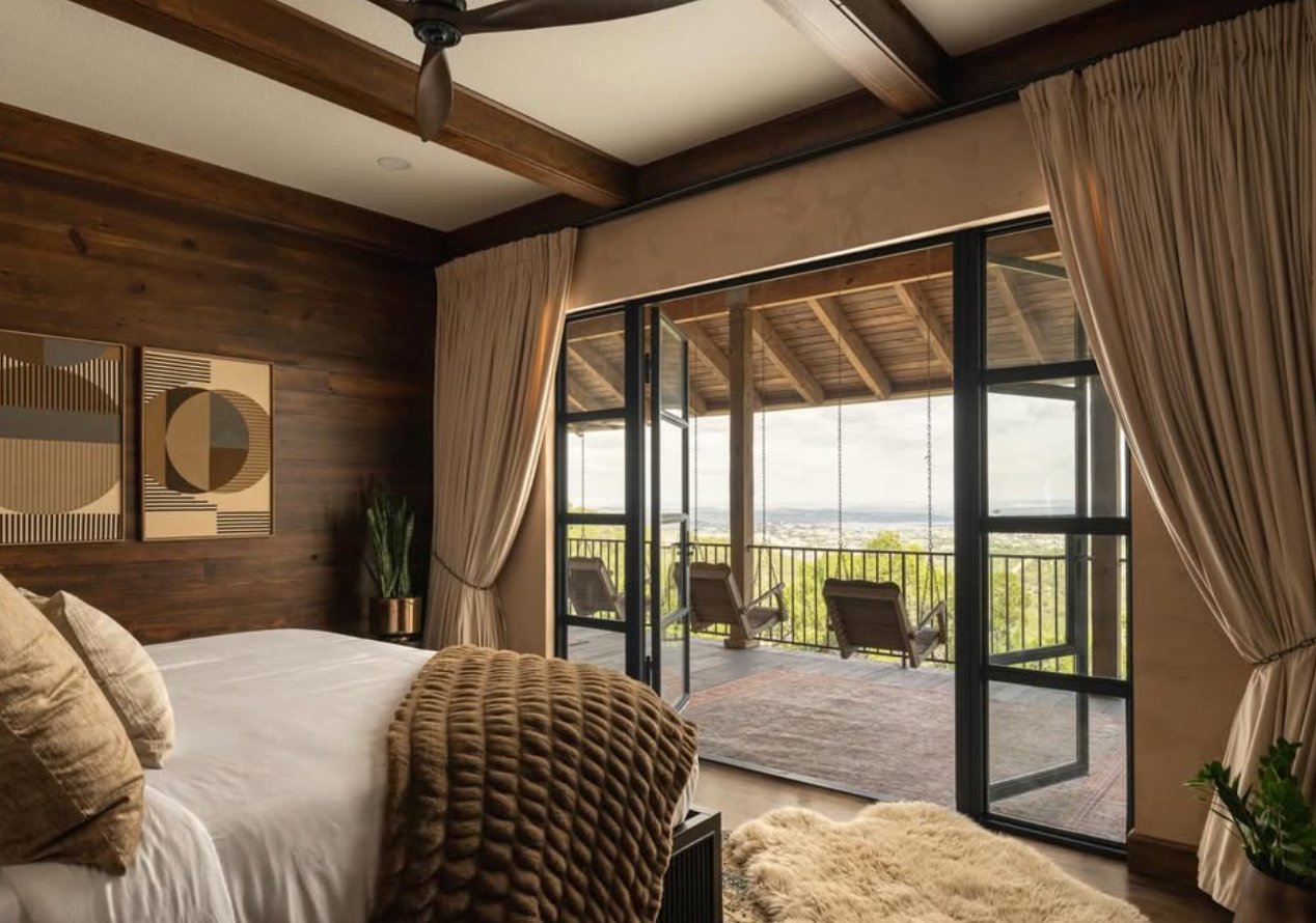 Bedroom with balcony, swing chairs, and long hill-country views