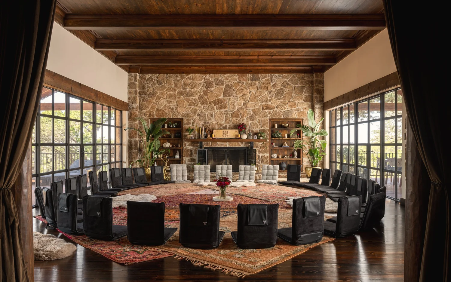 HAVAN Estate main hall — circle of black floor chairs and stone fireplace