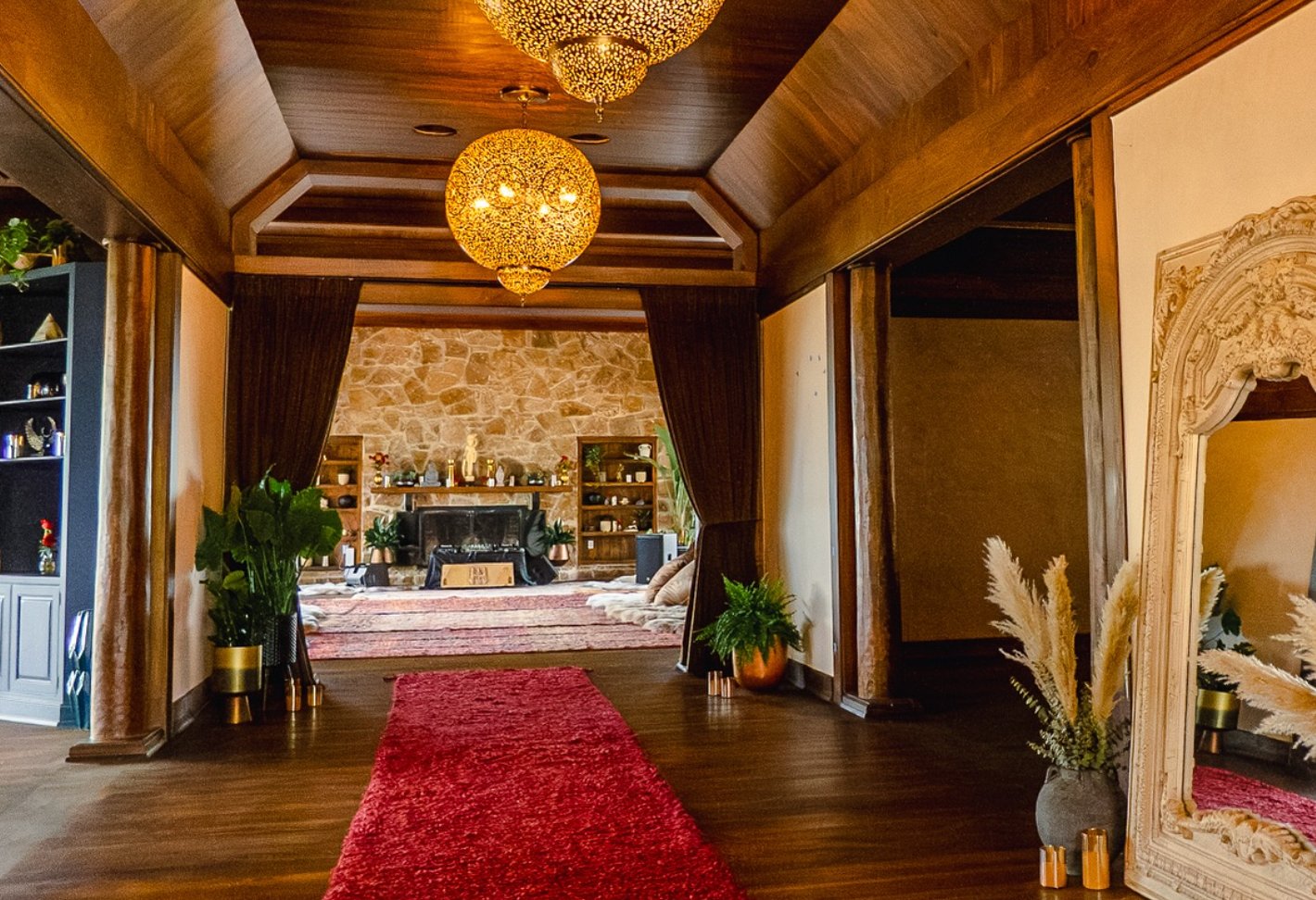 Entrance hall with brass lanterns, a red rug runner, and a fireplace altar
