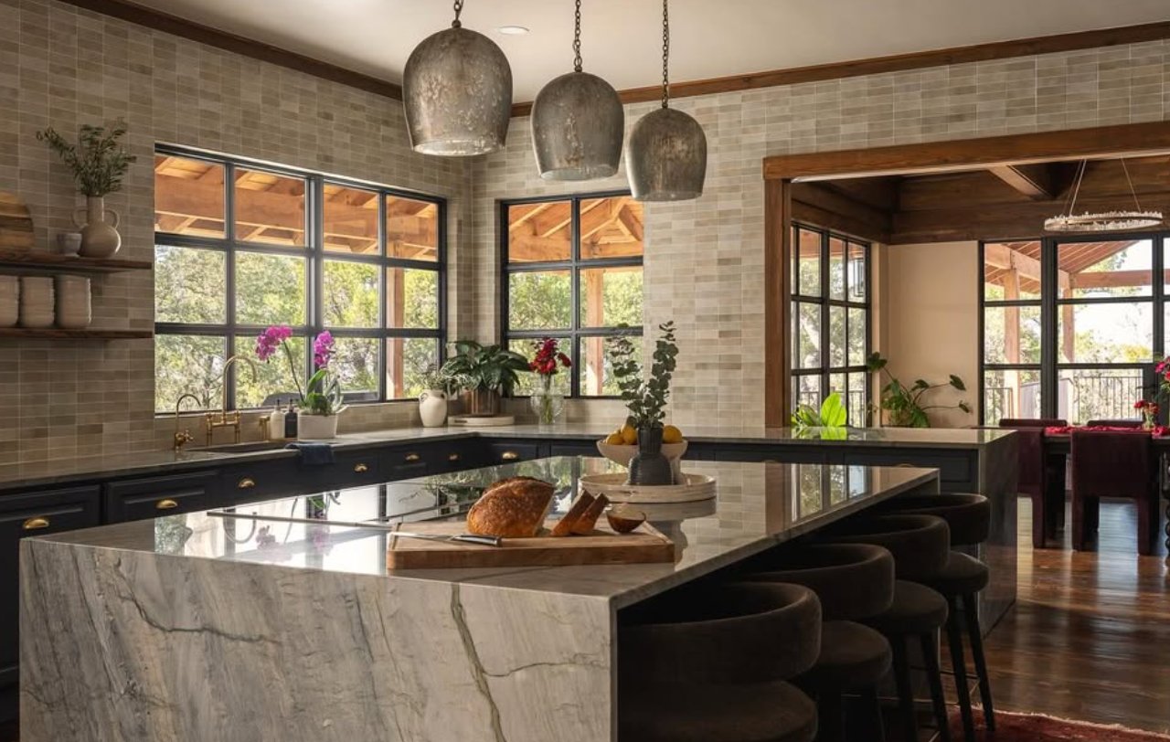 Kitchen with marble island, bell pendants, and dark cabinetry